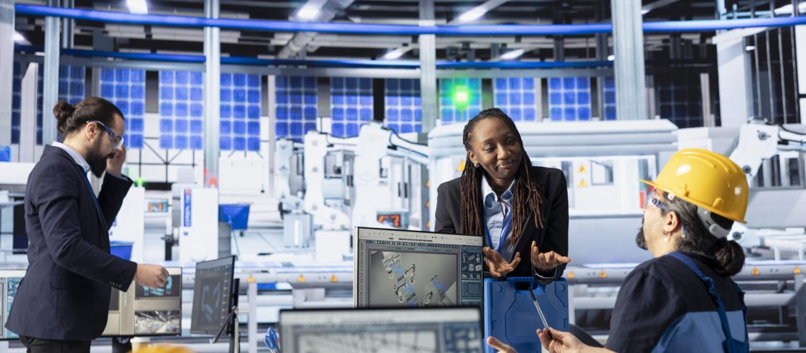 Solar panels plant engineering team doing quality control using computer, ensuring high efficiency. Photovoltaics factory teamworking colleagues calibrating assembly lines robotic arms